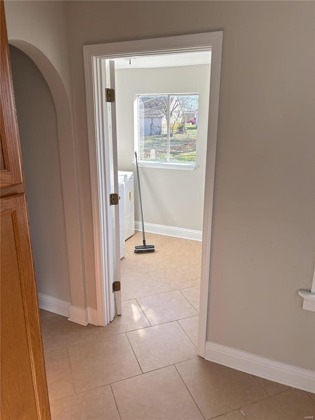 corridor with washer / clothes dryer and light tile patterned floors