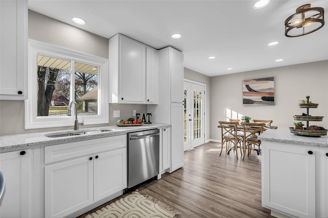 kitchen featuring sink, white cabinets, stainless steel dishwasher, and light wood-type flooring