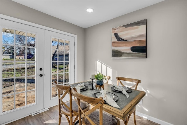 dining room featuring hardwood / wood-style floors, a healthy amount of sunlight, and french doors