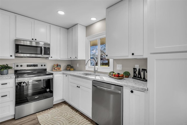 kitchen with sink, white cabinets, stainless steel appliances, and light hardwood / wood-style floors