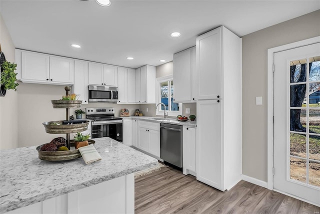 kitchen with white cabinetry, light hardwood / wood-style flooring, sink, and appliances with stainless steel finishes