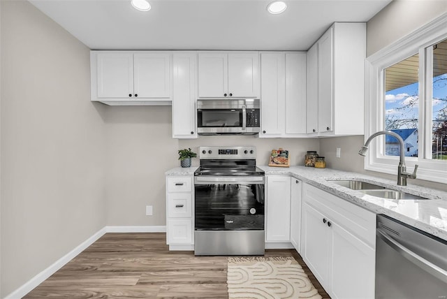 kitchen featuring white cabinetry, sink, appliances with stainless steel finishes, and light hardwood / wood-style flooring