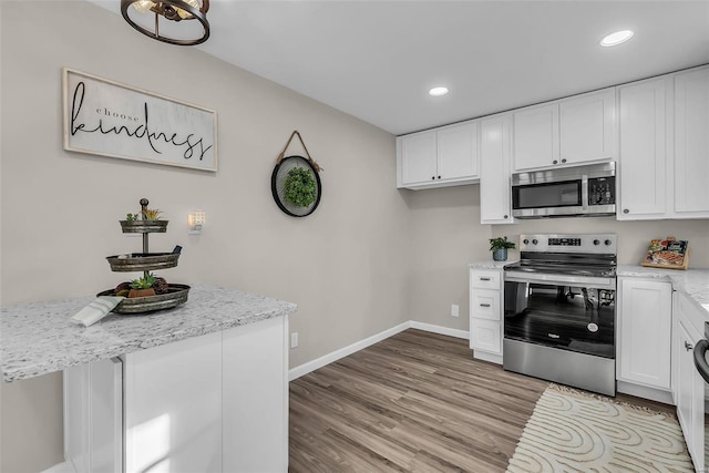 kitchen featuring white cabinets, stainless steel appliances, light hardwood / wood-style flooring, and light stone counters