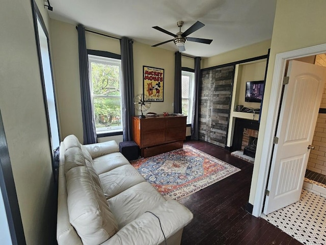 living area with hardwood / wood-style floors, a brick fireplace, and a ceiling fan