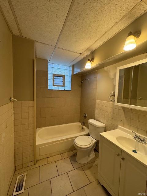 full bathroom with tile patterned floors, vanity,  shower combination, tile walls, and toilet