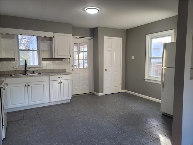 kitchen with a wealth of natural light, white cabinetry, sink, and decorative backsplash