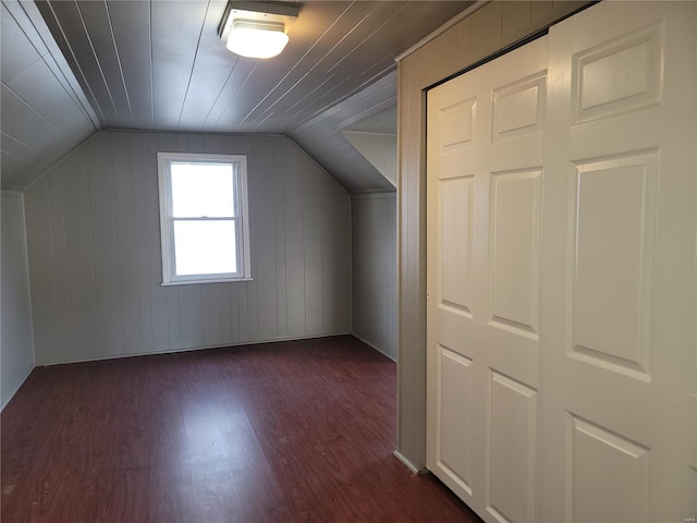 additional living space with wood walls, dark hardwood / wood-style flooring, and vaulted ceiling