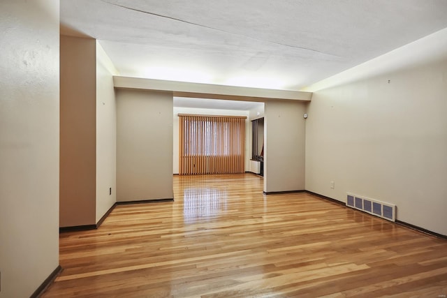 spare room featuring light wood-type flooring and a textured ceiling