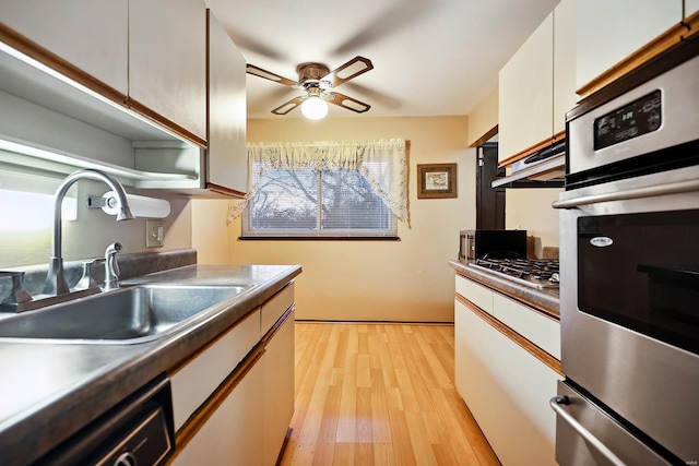 kitchen featuring white cabinets, sink, light hardwood / wood-style flooring, ceiling fan, and stainless steel appliances