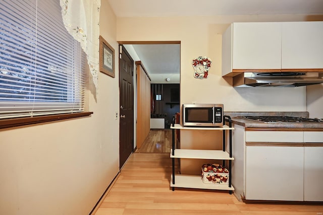 kitchen featuring white cabinets, exhaust hood, appliances with stainless steel finishes, and light hardwood / wood-style flooring