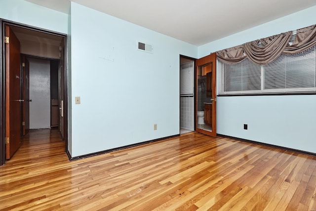 unfurnished bedroom featuring ensuite bathroom and light hardwood / wood-style floors