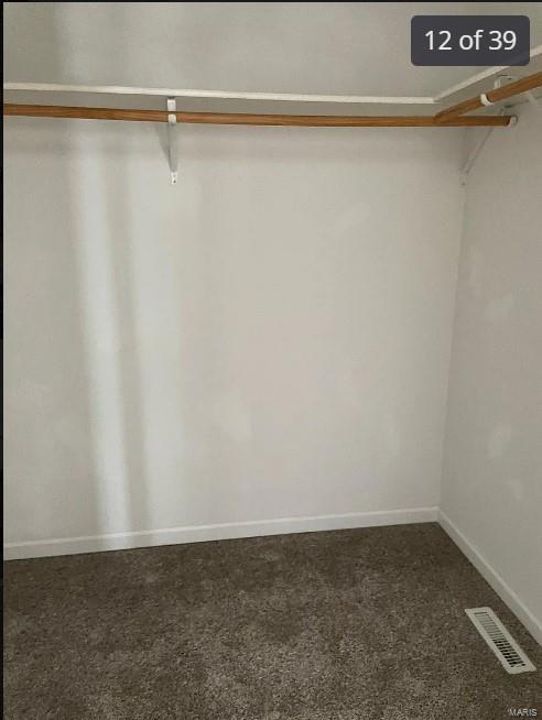 walk in closet featuring dark carpet