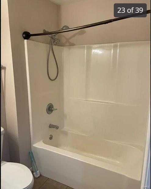 bathroom with toilet,  shower combination, and tile patterned floors