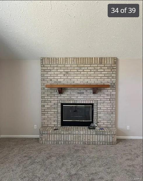 interior details featuring carpet flooring, a fireplace, and a textured ceiling