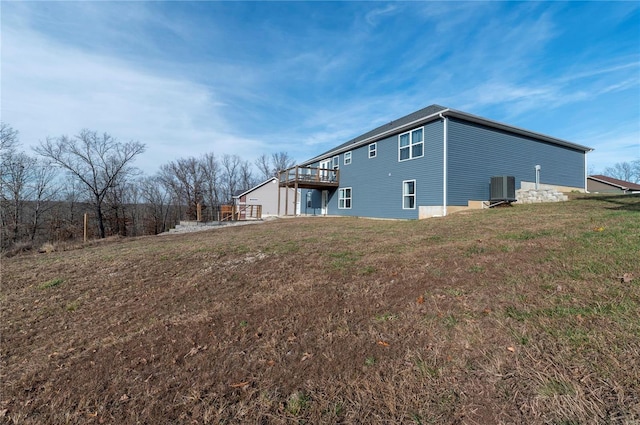 rear view of property featuring a lawn, central AC, and a wooden deck