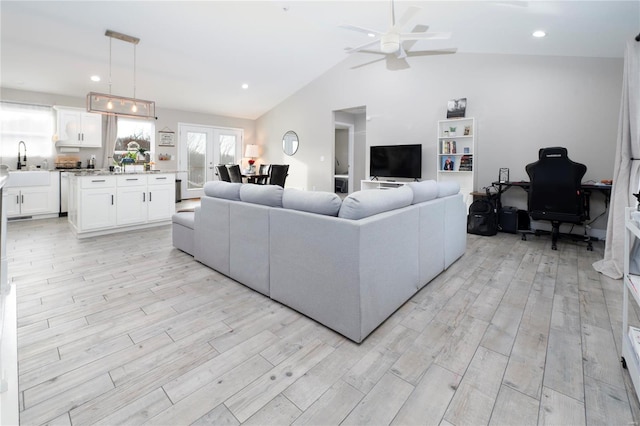 living room featuring ceiling fan, light hardwood / wood-style flooring, vaulted ceiling, and sink