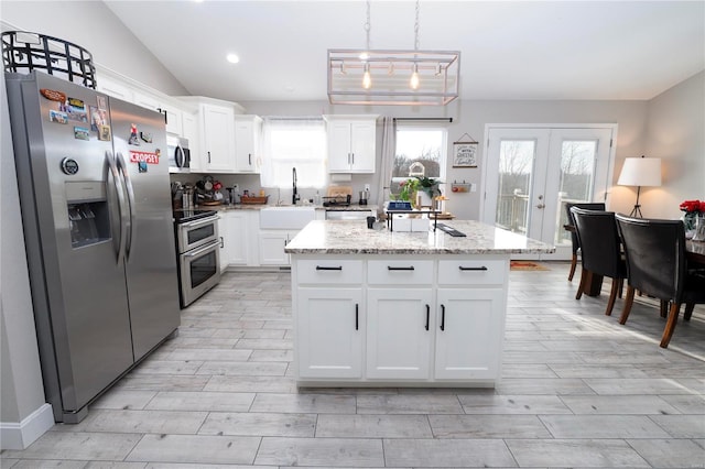 kitchen featuring white cabinetry, hanging light fixtures, appliances with stainless steel finishes, and vaulted ceiling