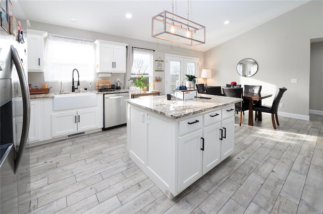 kitchen with pendant lighting, white cabinetry, sink, and appliances with stainless steel finishes