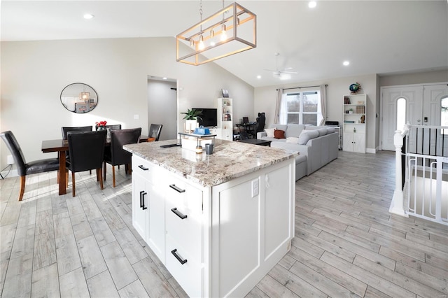 kitchen with light hardwood / wood-style flooring, a center island, white cabinetry, hanging light fixtures, and lofted ceiling