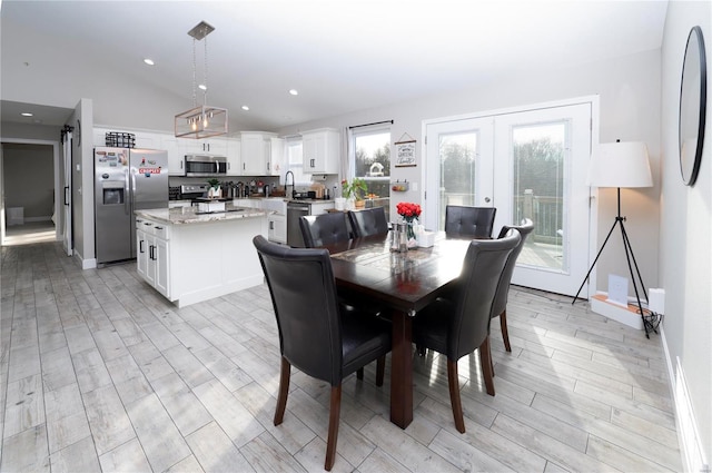 dining area featuring light hardwood / wood-style floors, lofted ceiling, and french doors