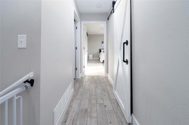 hallway featuring a barn door and light hardwood / wood-style flooring