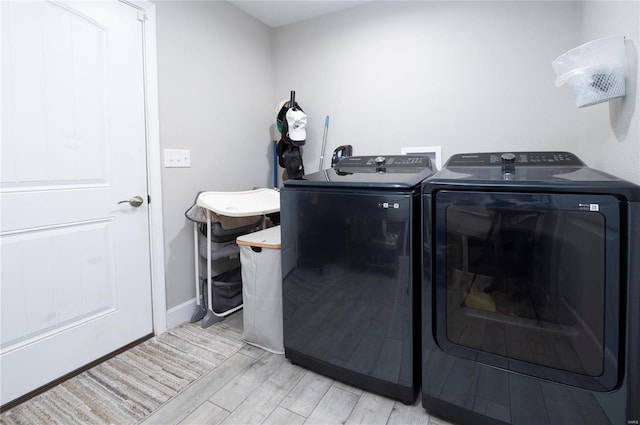 clothes washing area featuring washing machine and dryer and light hardwood / wood-style flooring