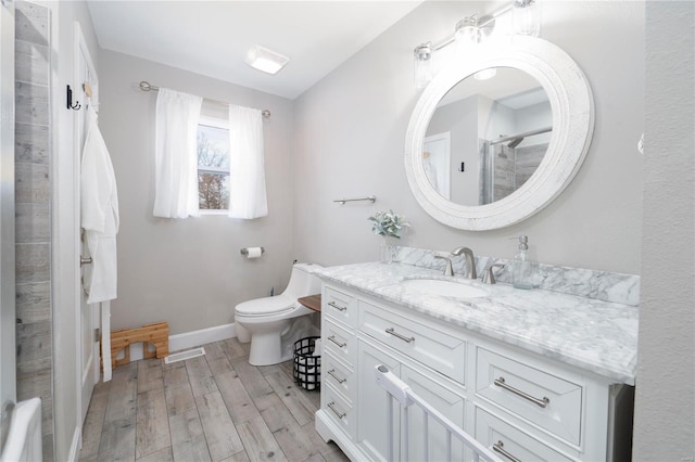 bathroom featuring a shower, vanity, hardwood / wood-style flooring, and toilet