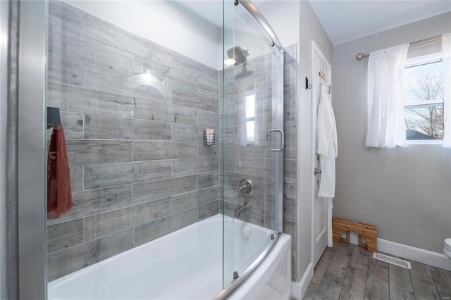 bathroom with wood-type flooring, toilet, and enclosed tub / shower combo