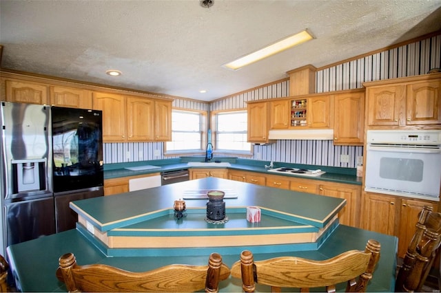 kitchen with black fridge with ice dispenser, a center island, a textured ceiling, and oven