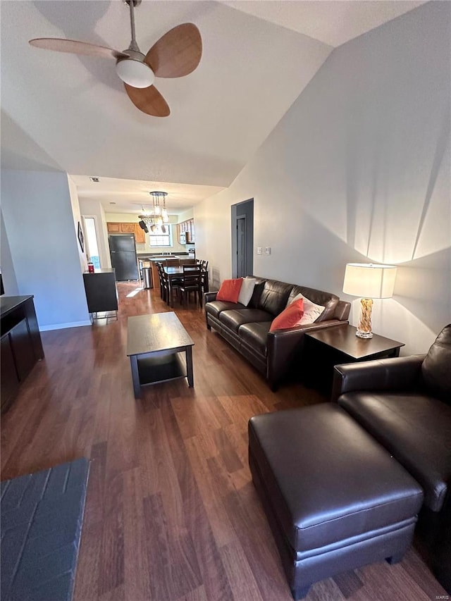 living room featuring ceiling fan with notable chandelier, dark hardwood / wood-style floors, and lofted ceiling