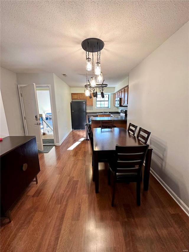 dining room with wood-type flooring and a textured ceiling