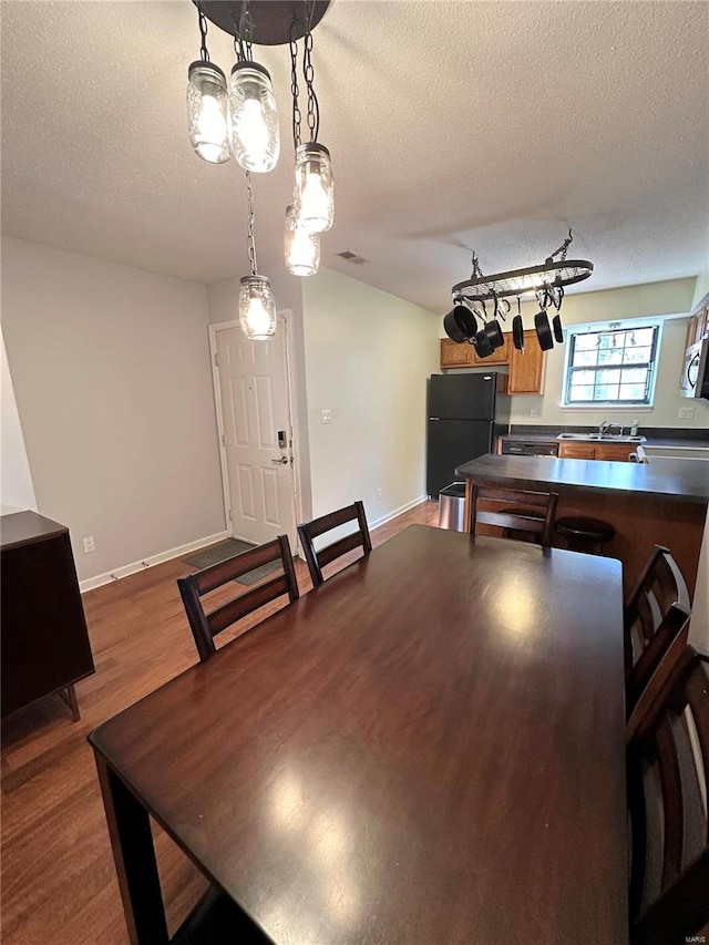 dining room featuring sink, a textured ceiling, and hardwood / wood-style flooring