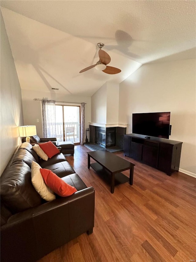 living room with ceiling fan, wood-type flooring, a textured ceiling, and vaulted ceiling