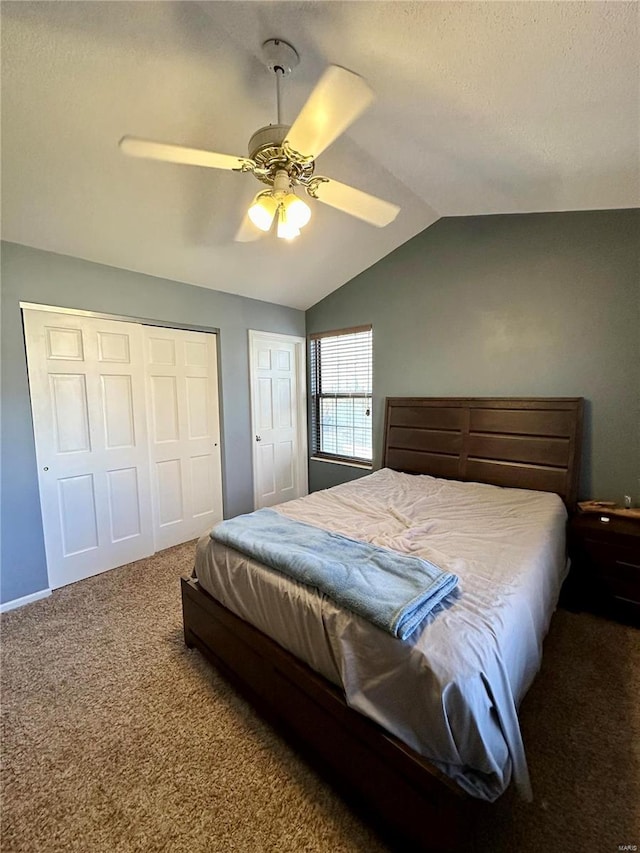 bedroom with dark colored carpet, ceiling fan, a closet, and vaulted ceiling