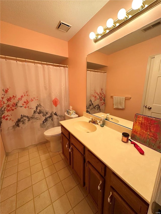 bathroom with tile patterned floors, vanity, a textured ceiling, and toilet