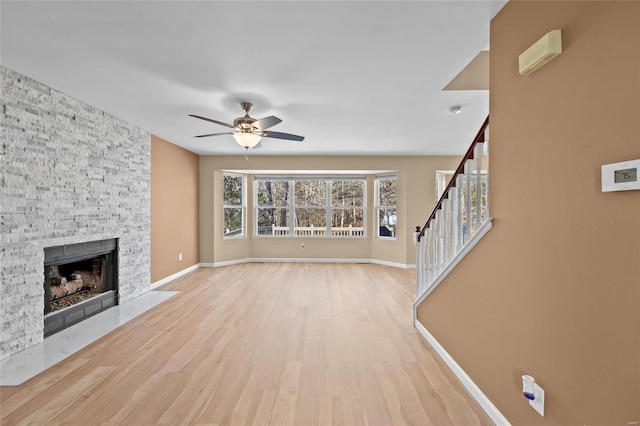 unfurnished living room with ceiling fan, a fireplace, and light wood-type flooring