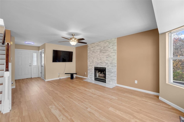 unfurnished living room with a fireplace, light wood-type flooring, and ceiling fan