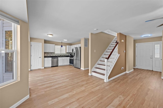 kitchen featuring white cabinets, appliances with stainless steel finishes, backsplash, and a wealth of natural light