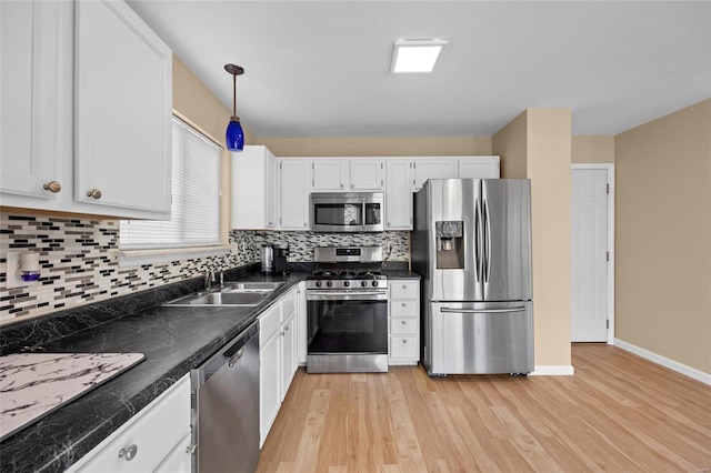 kitchen featuring white cabinets, tasteful backsplash, decorative light fixtures, light hardwood / wood-style floors, and stainless steel appliances