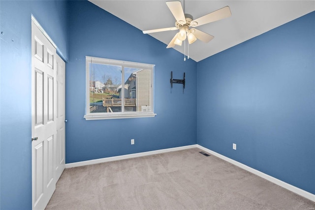 empty room featuring light carpet, ceiling fan, and lofted ceiling