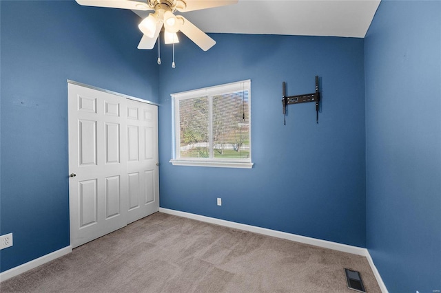 unfurnished bedroom with ceiling fan, a closet, light colored carpet, and vaulted ceiling