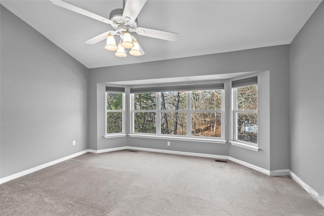 carpeted spare room with a wealth of natural light, lofted ceiling, and ceiling fan