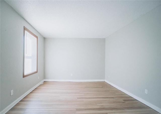 spare room featuring a textured ceiling and light hardwood / wood-style floors