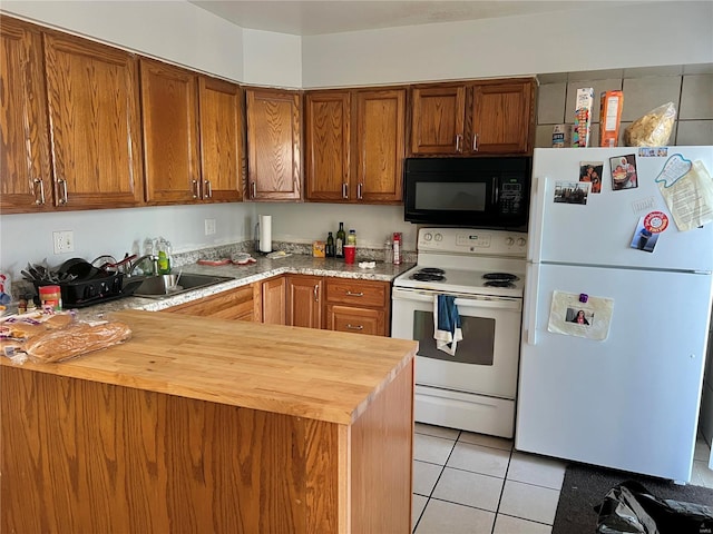 kitchen with light tile patterned floors, white appliances, butcher block countertops, and sink