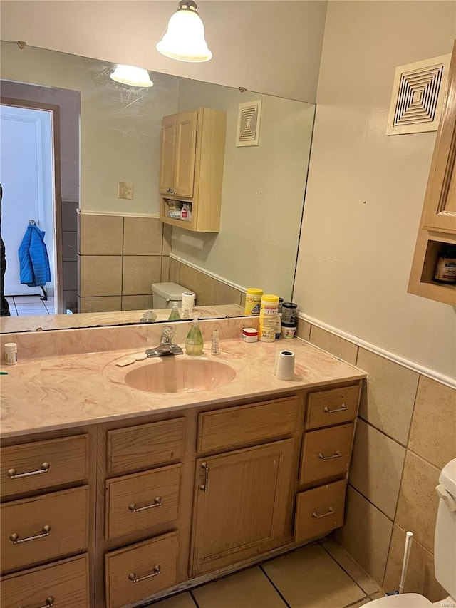 bathroom featuring tile patterned floors, vanity, toilet, and tile walls