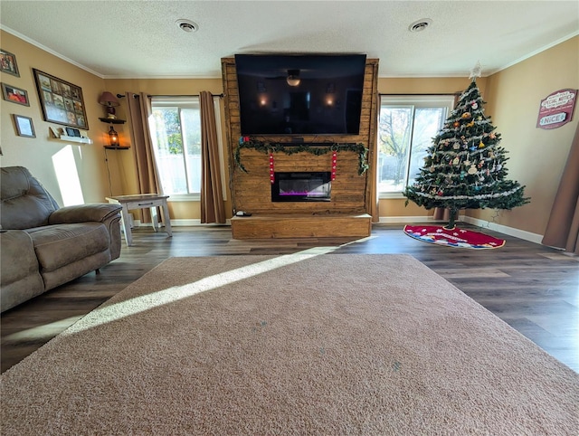 living room featuring dark hardwood / wood-style floors, crown molding, plenty of natural light, and a textured ceiling