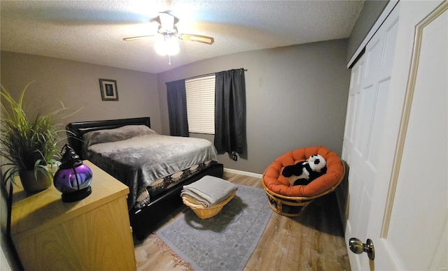 bedroom featuring ceiling fan, light wood-type flooring, a textured ceiling, and a closet