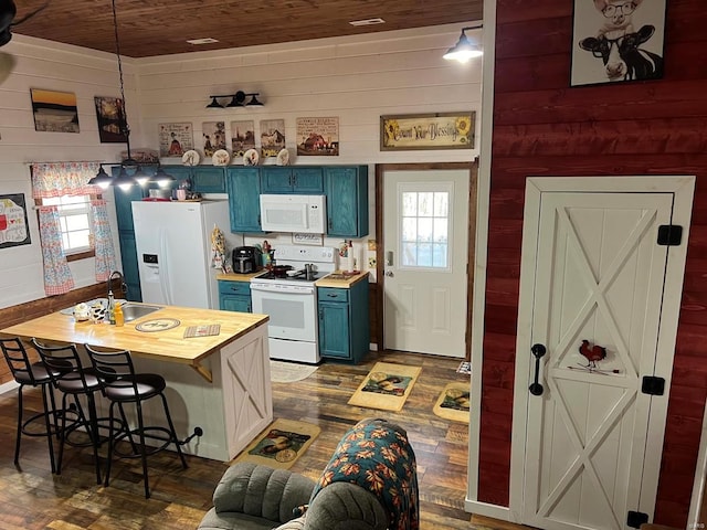 kitchen with wood walls, sink, white appliances, and blue cabinets