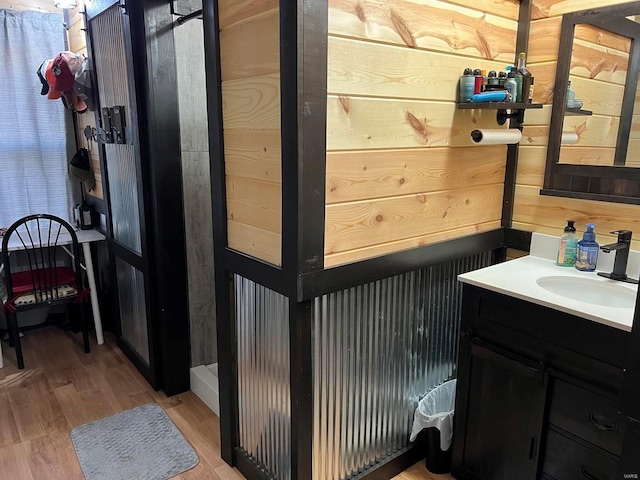 bathroom featuring vanity, hardwood / wood-style flooring, and wood walls