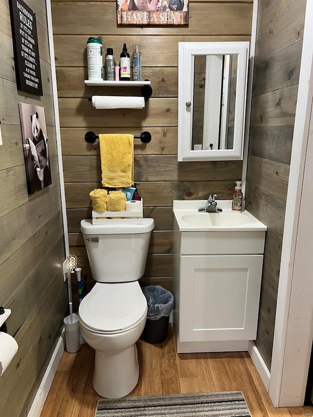 bathroom featuring wood walls, toilet, vanity, and hardwood / wood-style flooring